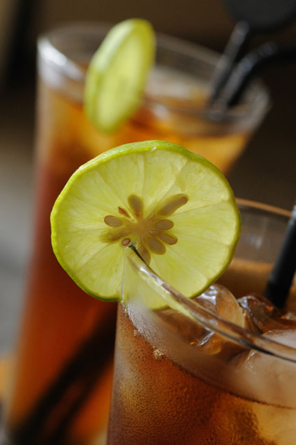 A close up of two glasses of iced tea with a lemon slice on the rim of the glass