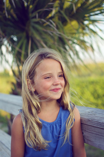 A little girl smiling with a palm tree in the background