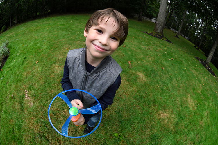 A fisheye effect on a young boy playing with a toy in the yard