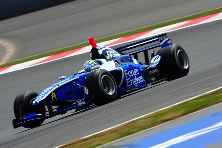 A dark blue formula one race car speeds around the track