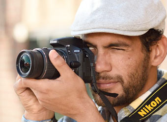 Image of a man taking a photograph with a DSLR Camera.