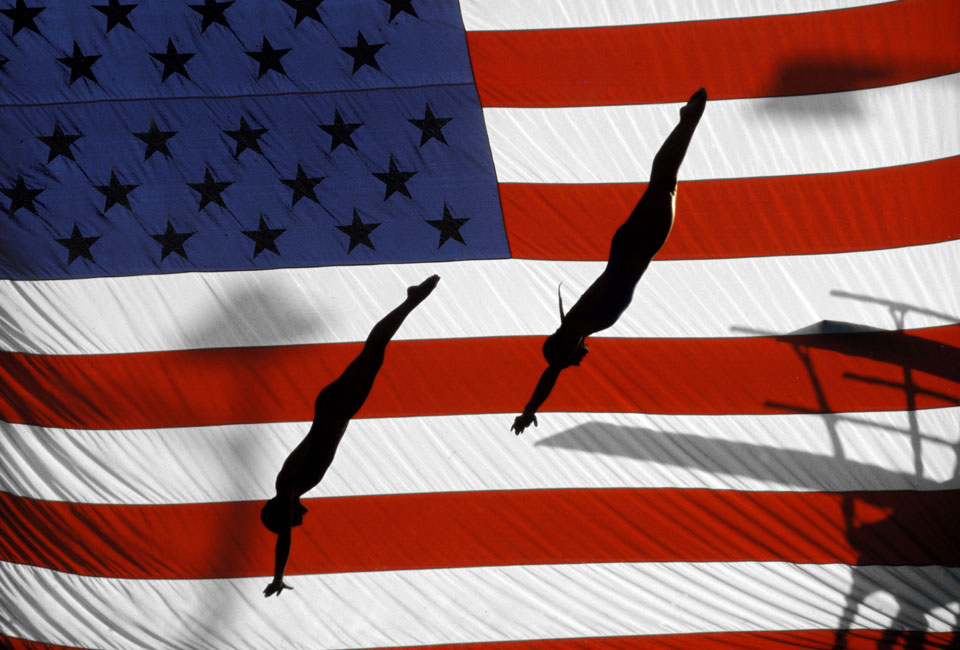 Bill Frakes sports photograph of synchronized divers silhouetted against an American flag