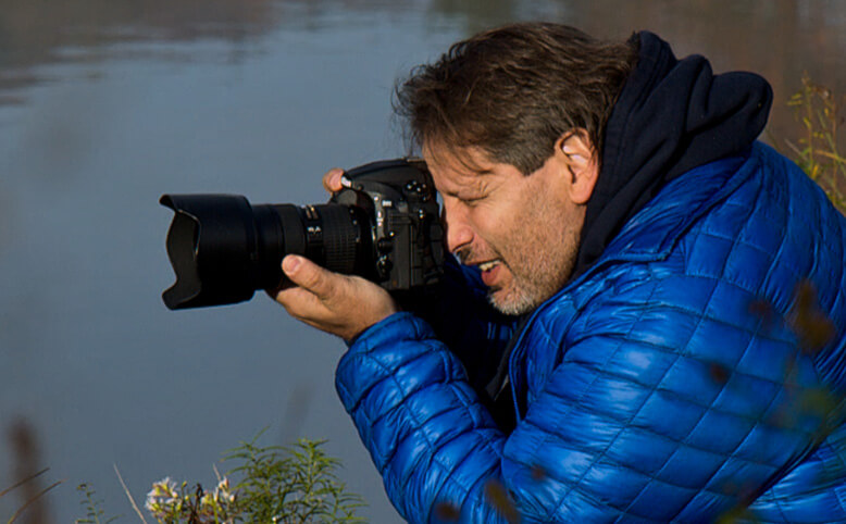 Photographe regardant dans le viseur d’un reflex numérique Nikon avec un objectif FX NIKKOR