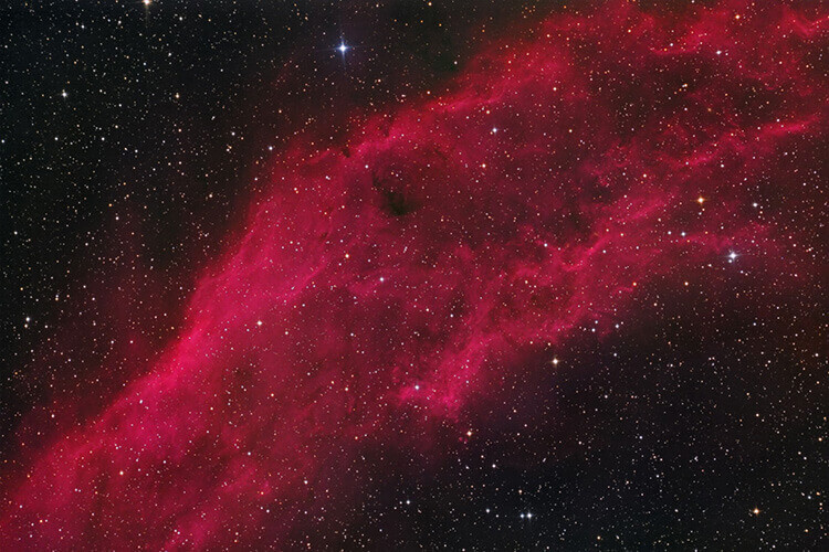 An astrophotography shot of a reddish nebula in the night sky