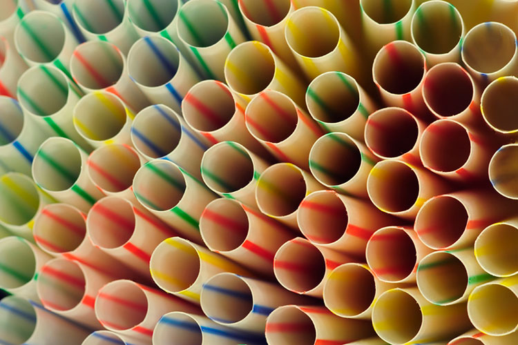 A close up of the circular openings of a pile of multi-colored drinking straws