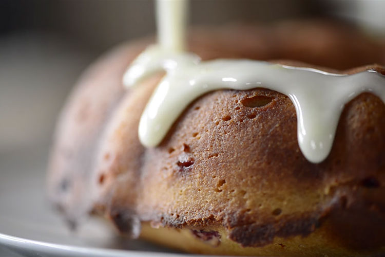 A close up of a pastry with white glazing being poured on top