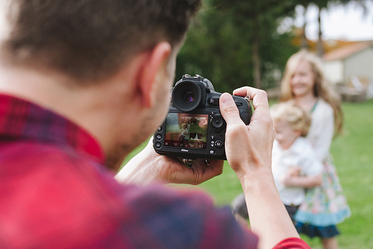 A father takes a photo of his children in the yard