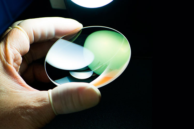 A hand holds a clean, reflective NIKKOR lens