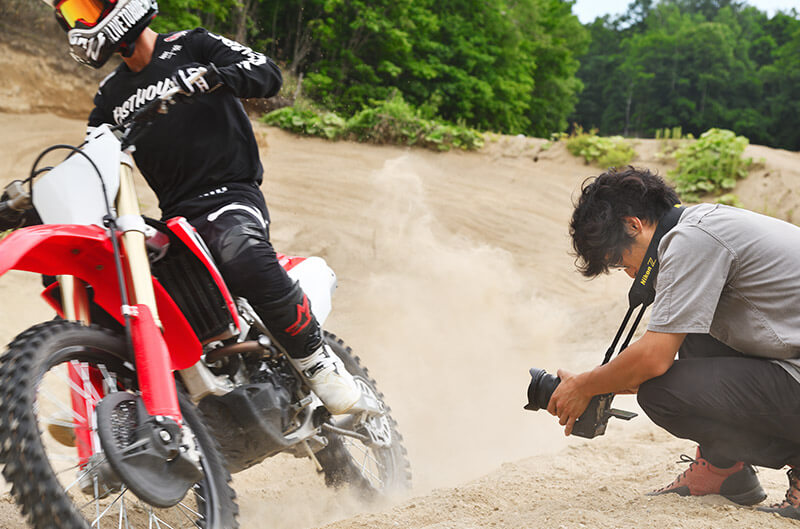 Photo of a photographer capturing a shot of a motorbike from a low angle, using the LCD