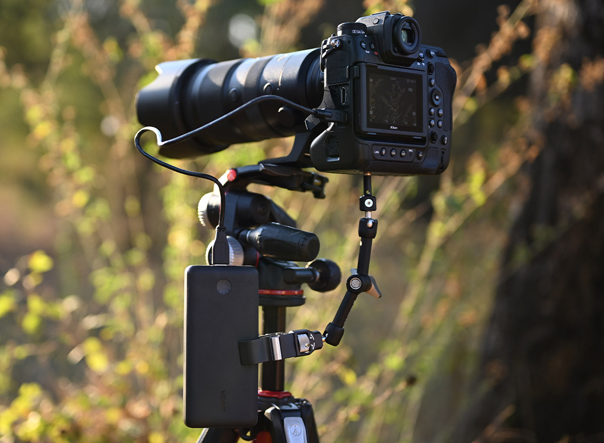 Photo of the Z 9 and telephoto lens on a tripod attached to a mobile battery via USB