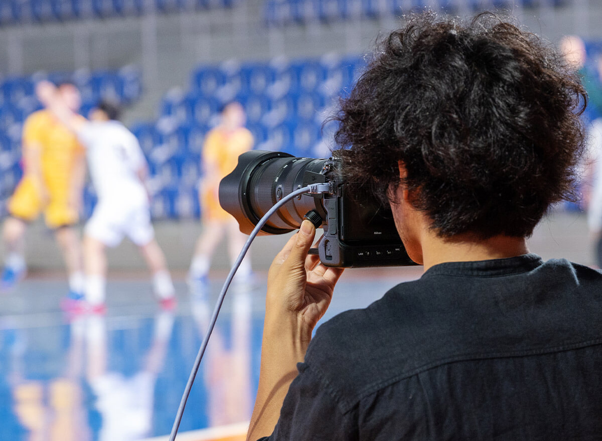Photo of a photographer shooting sports action with an ethernet cable attached to the camera