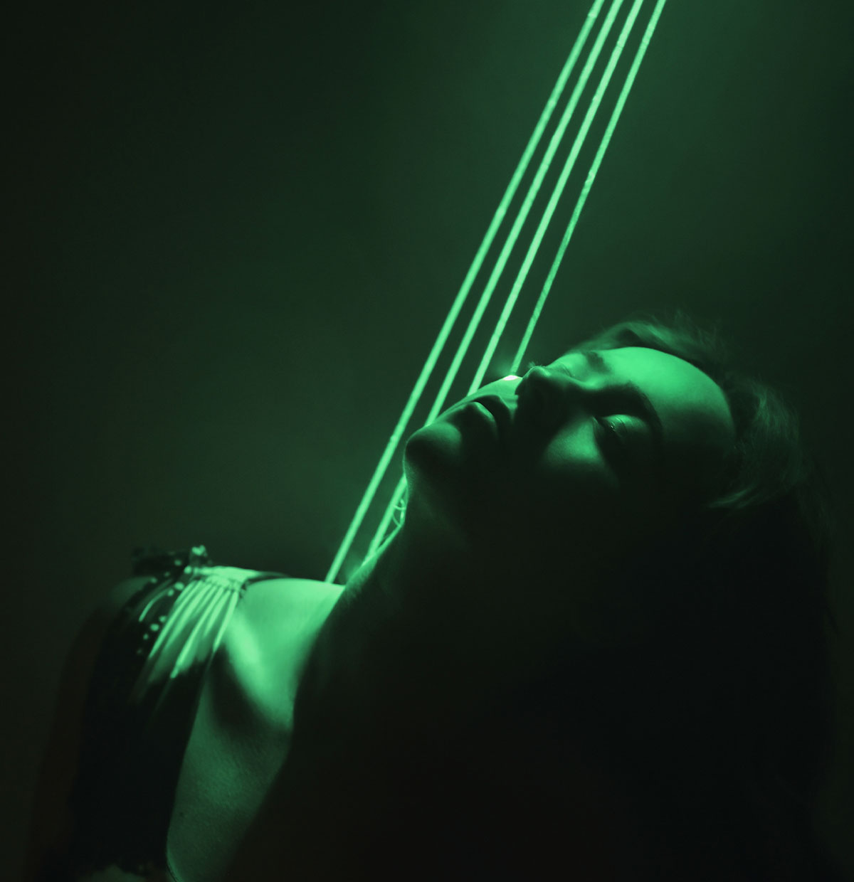 Photo of a woman in low light, lit by green light and showing four green streams of light in the backgorund, taken with the Z f camera