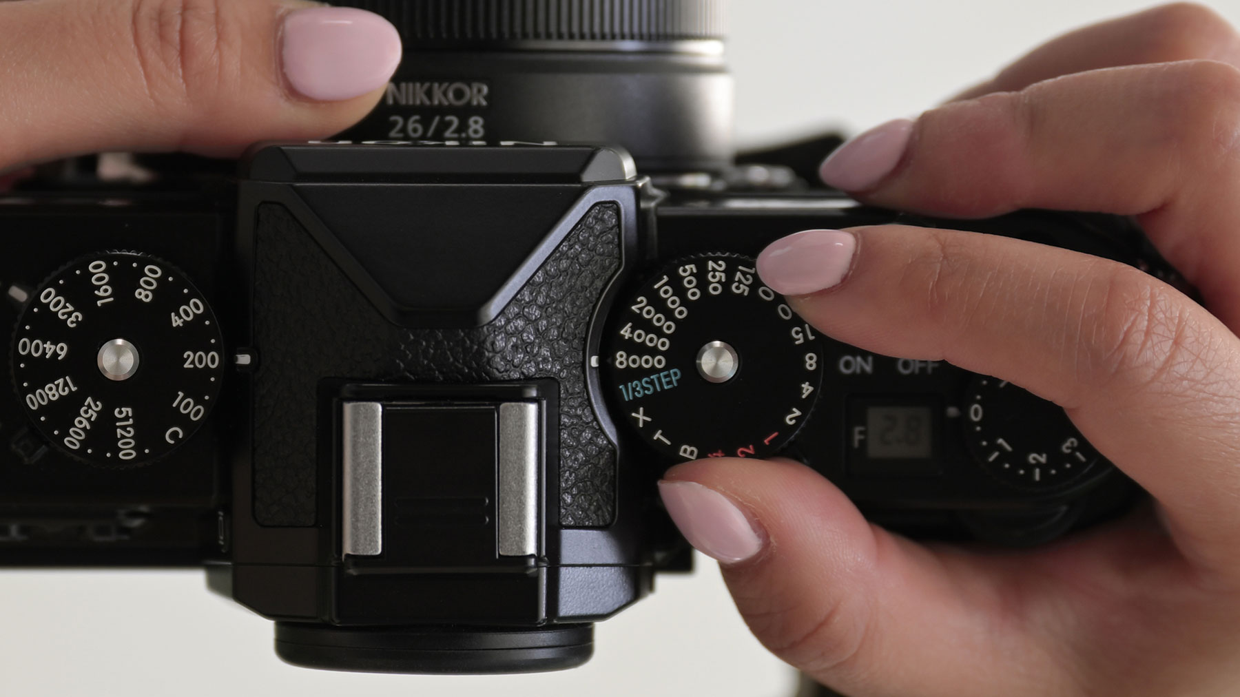 Photo of a pair of hands holding the Z f camera, adjusting the shutter speed dial