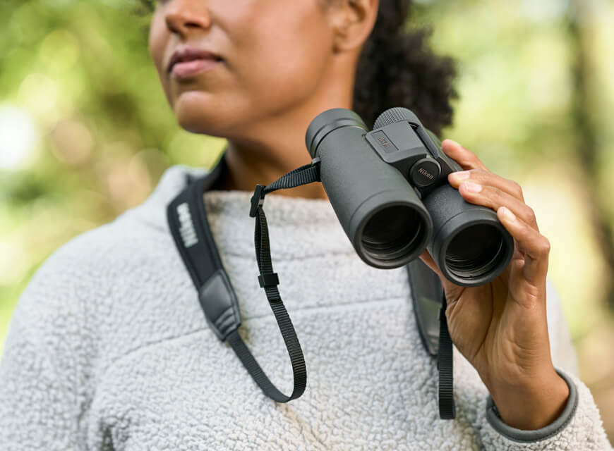 Foto di una donna con in mano un binocolo Monarch M5