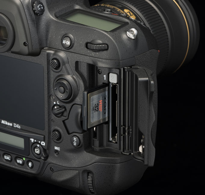 Rear of the Nikon D4S pro level DSLR camera with the door open to show the media card slots and an XQD card half in/half out