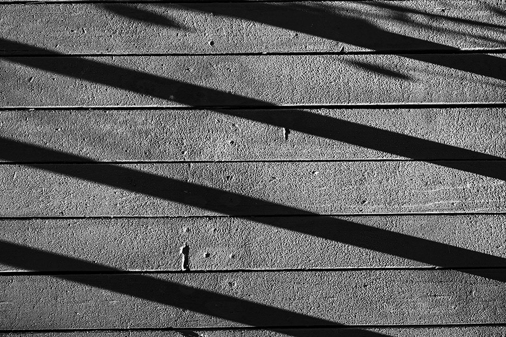 Tom Bol photo of a wooden deck with shadows, in B&W